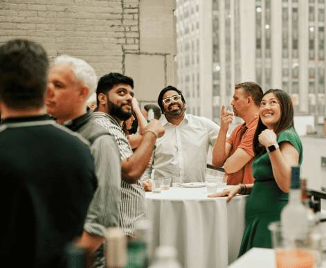 A diverse group of Media.net employees gathered in their office, smiling and posing around a table with a dessert tray, reflecting a collaborative and welcoming workspace.