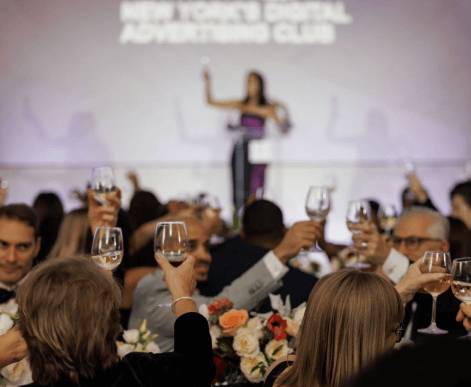 Three Media.net team members collaborating at a conference table, smiling and discussing work over laptops and notebooks, in a professional yet comfortable office setting.