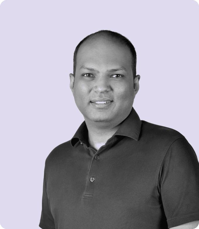 Black-and-white portrait of Vaibhav Arya, CEO of Media.net, smiling confidently, wearing a casual polo shirt, set against a soft lavender backdrop.